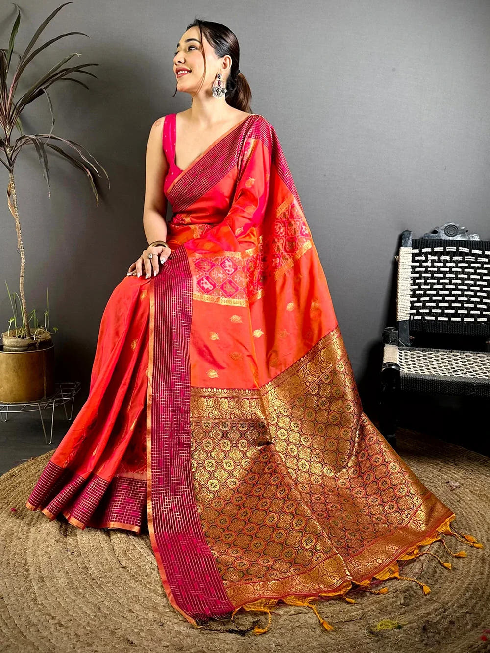 Red-orange Soft Silk Ikkat Pochampally saree, seated pose showing the pallu with resham tassels at the end