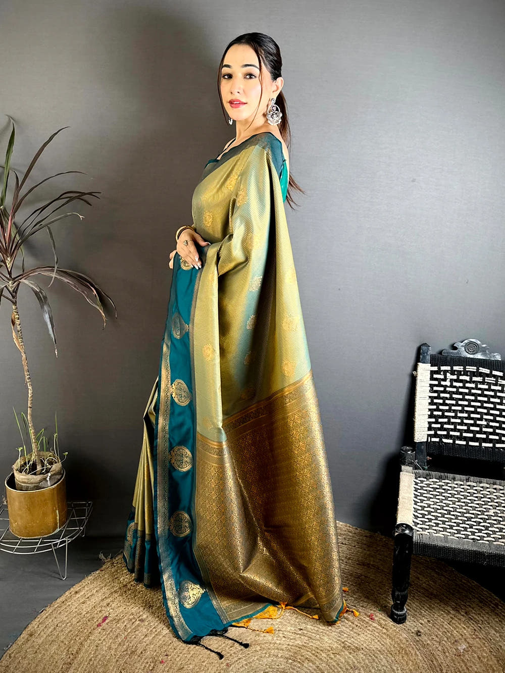 Sage green tissue zari saree, side view showing the pallu drape and tassels with the teal border