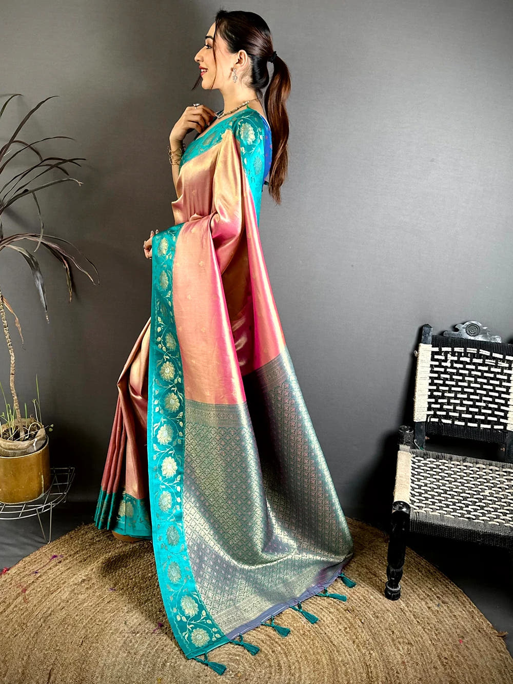 Pink soft tissue zari buti saree, side view showing teal border and zari woven pallu with tassels