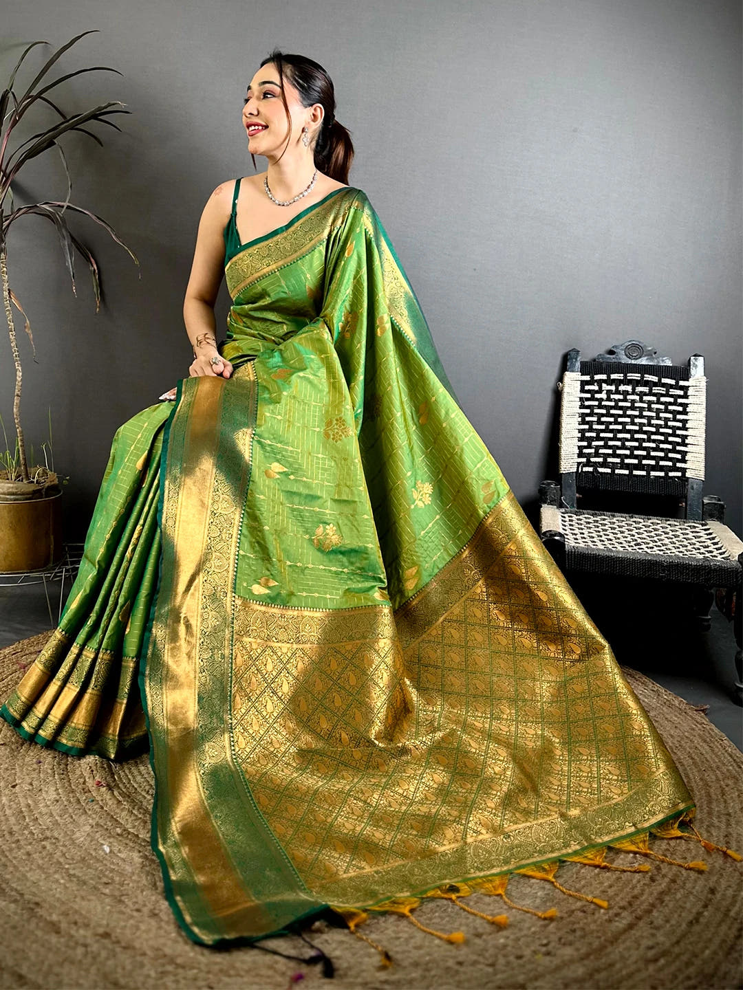 Green soft silk kanchi pattu-style saree, seated pose with the pallu and tassels spread out on a jute mat