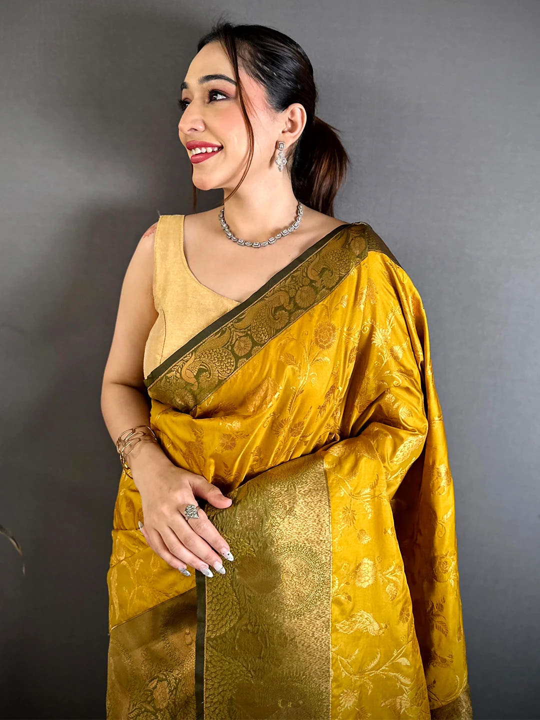Mustard yellow soft silk zari-style jaal saree, front drape on a model with olive-green peacock border and blouse