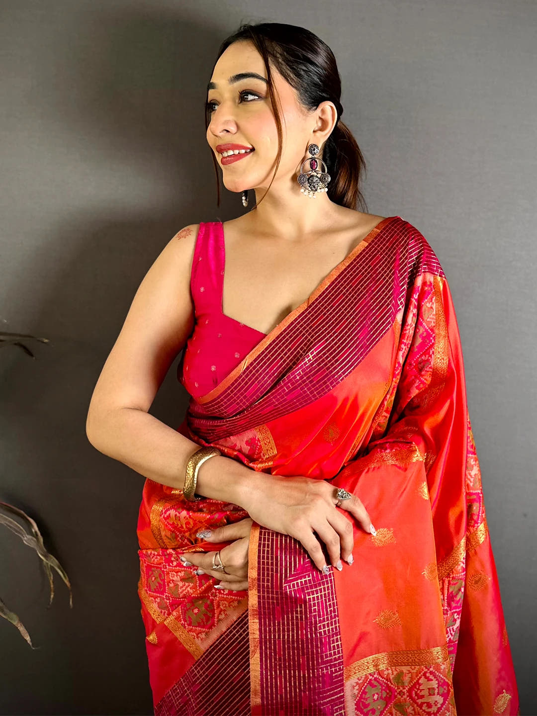 Red-orange Soft Silk Ikkat Pochampally saree, close-up front drape on model with magenta checked border and pink blouse
