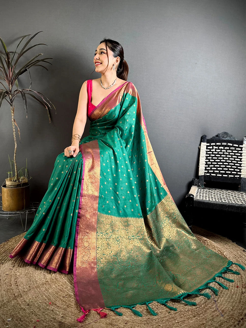 Teal Green Raw Silk Zari Buti Saree, seated model showing the zari-style border along the hem and the magenta edge