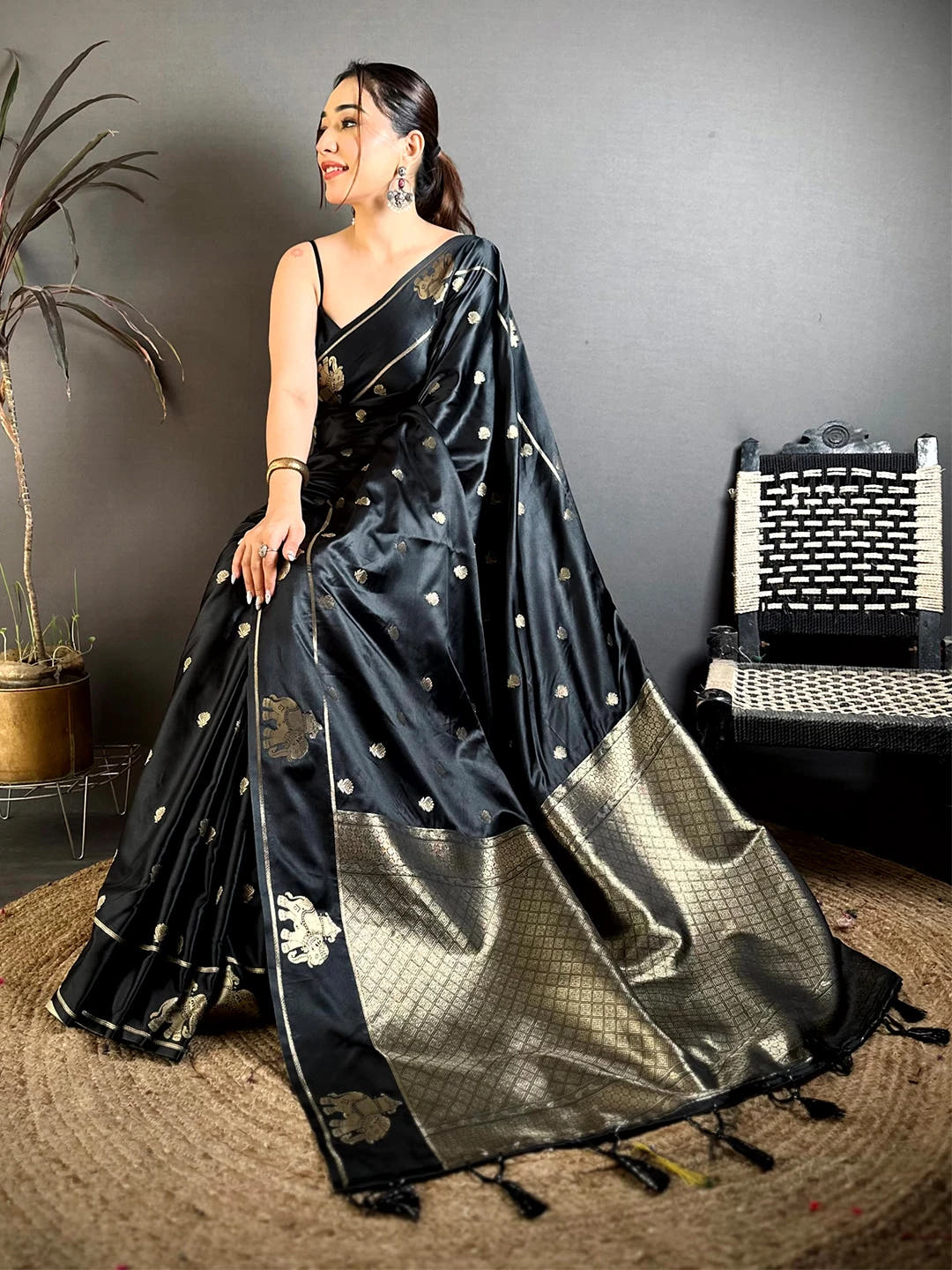 Black Mashru Satin Silk elephant zari butta saree, seated pose with the pallu falling down and tassels at the hem