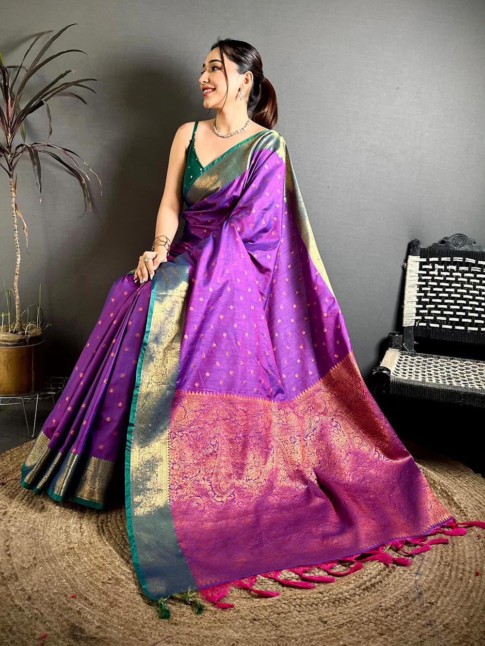Royal purple raw silk woven buti saree, seated pose showing the paisley-style woven pallu and tassel end