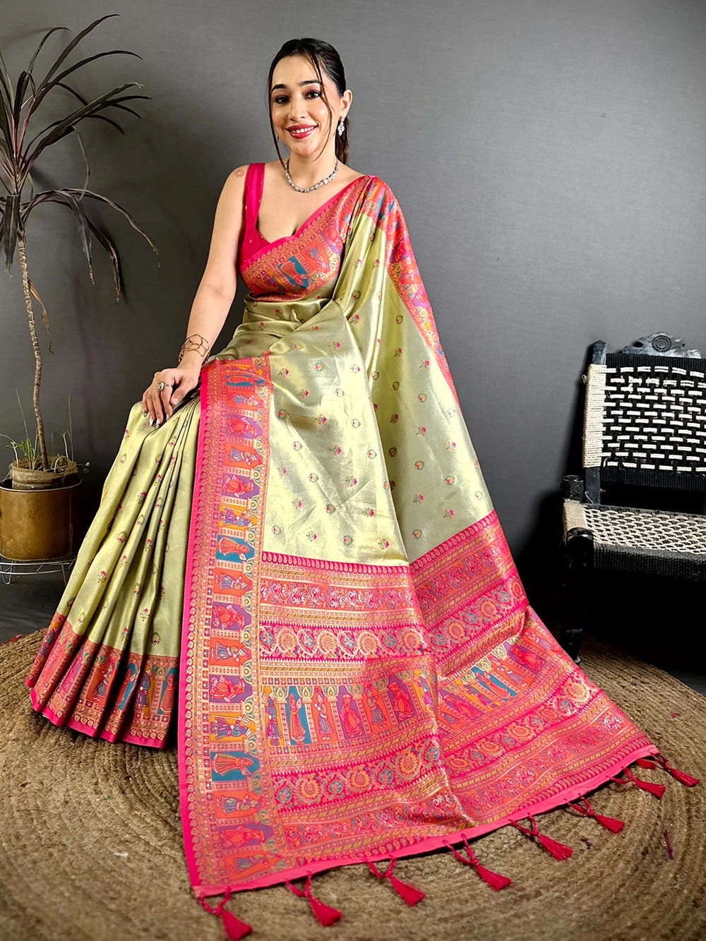 Pista green soft silk Dharmavaram-style saree, seated pose with pallu spread out showing woven figures and pink tassels