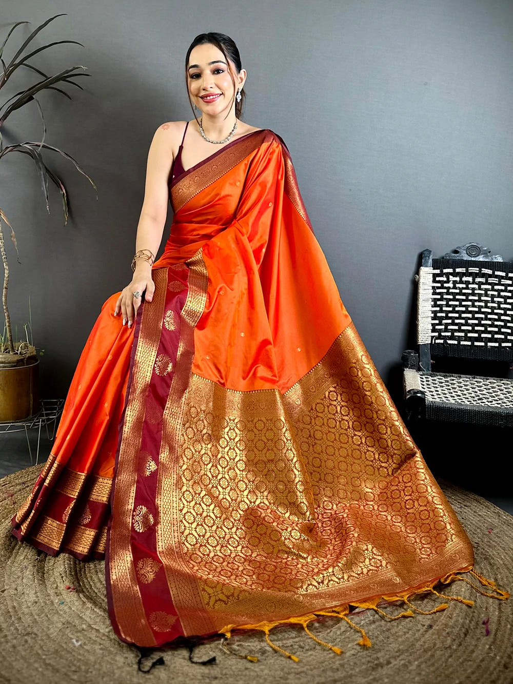 orange silk kanchi-style saree with maroon blouse piece, model posing full length with the broad woven pallu spread out