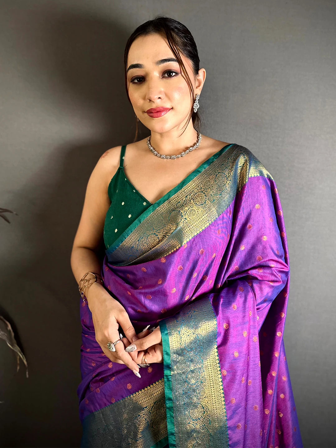 Royal purple raw silk woven buti saree, front close-up on model showing the zari-style border and green blouse piece