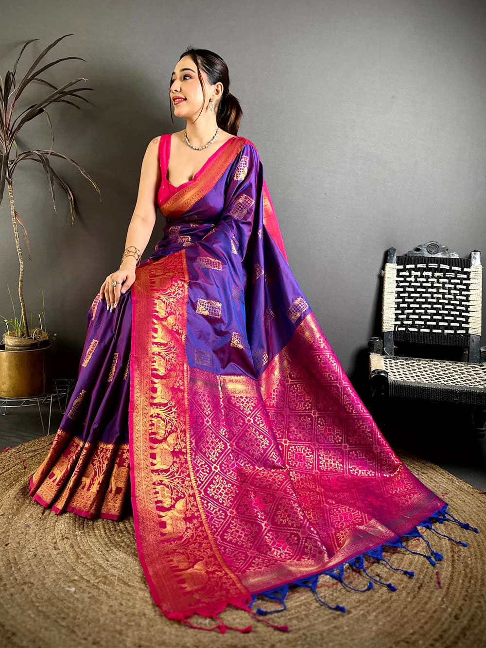 purple soft silk woven butta saree, model posing on jute rug showing the pink border and pallu drape
