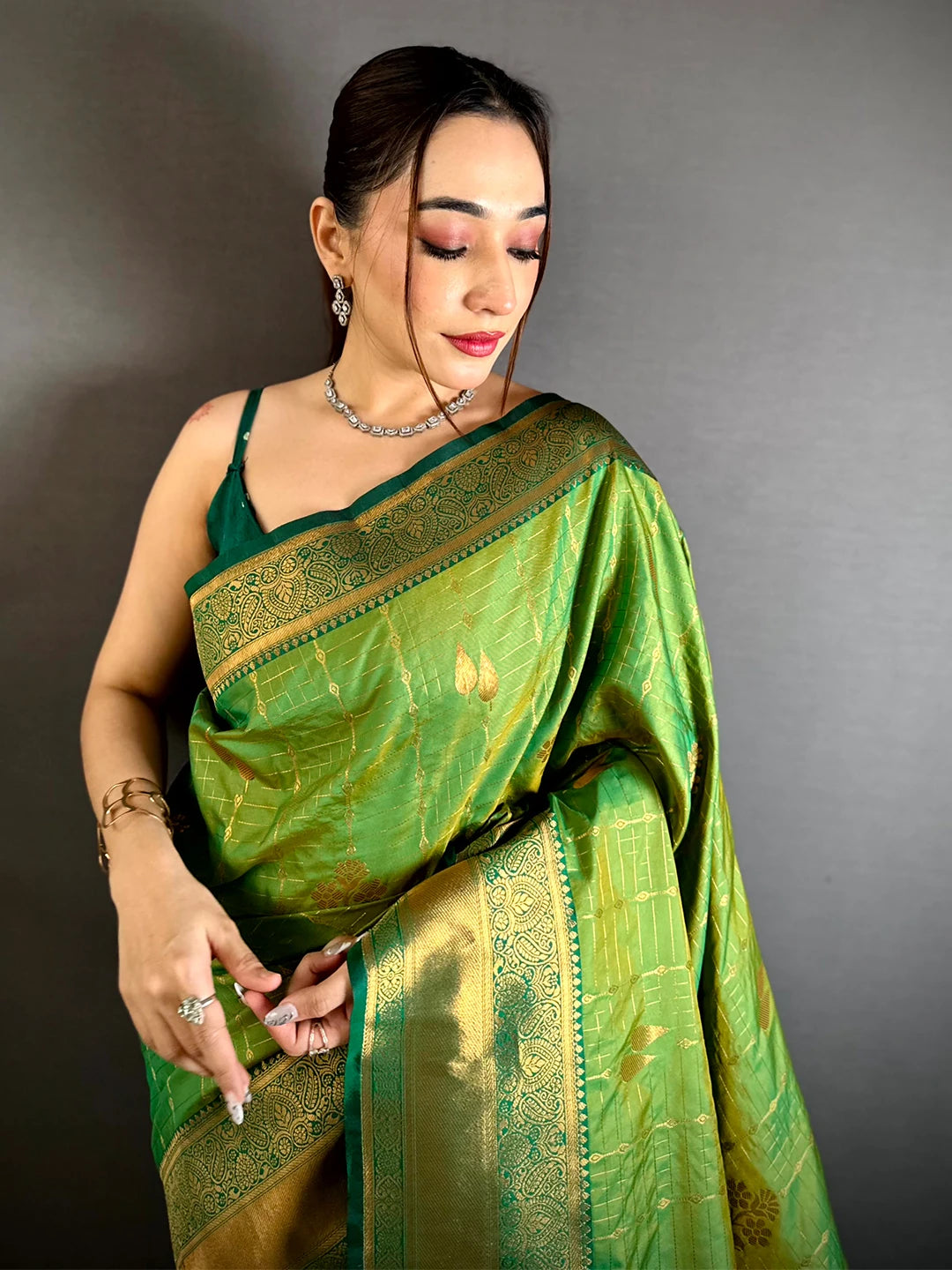 Green soft silk kanchi pattu-style saree, front drape on a model with gold checked butta grid and leaf motifs