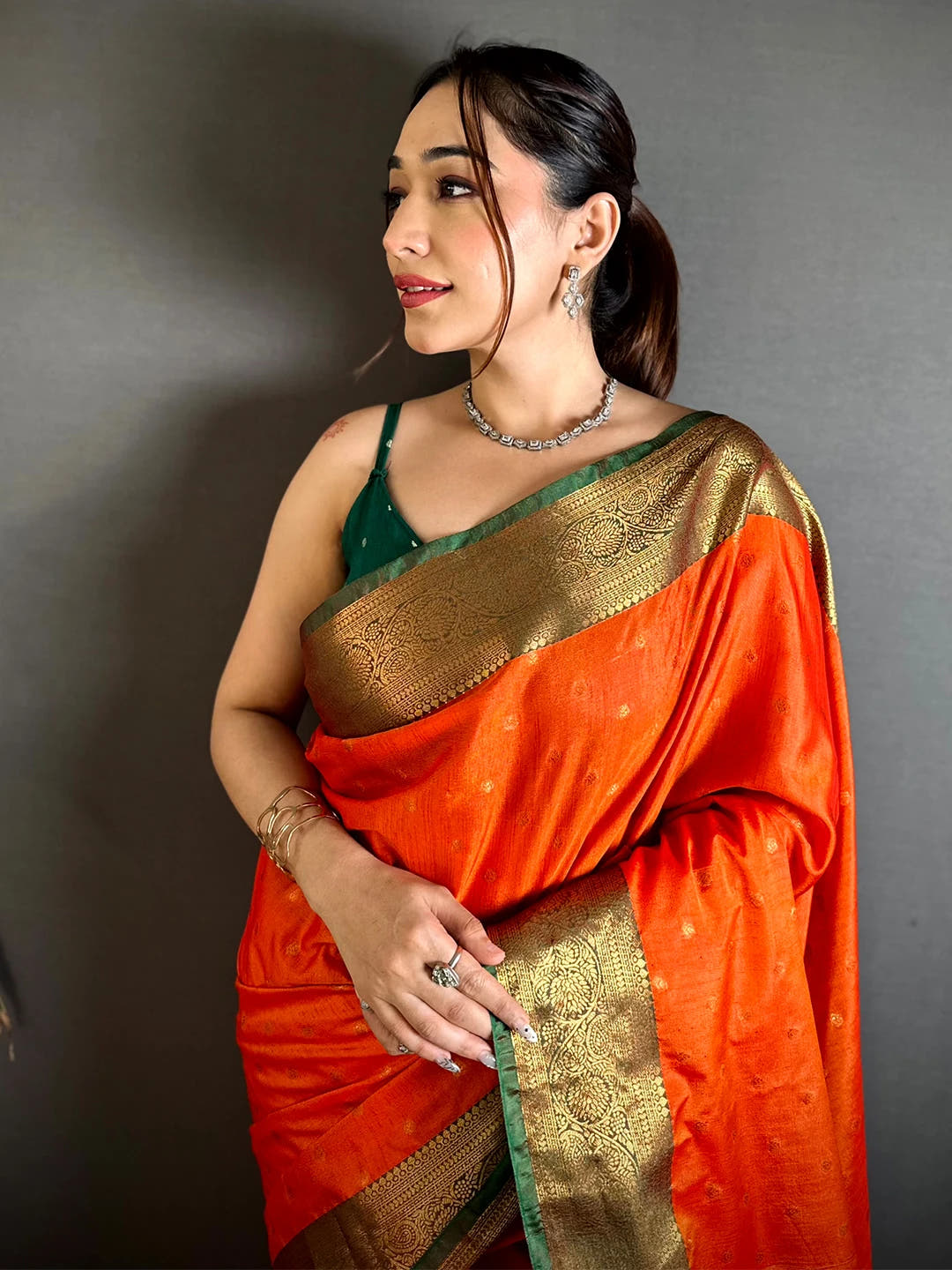 Royal orange raw silk woven buti saree, close-up of the zari-style border with fine green edge on the front drape
