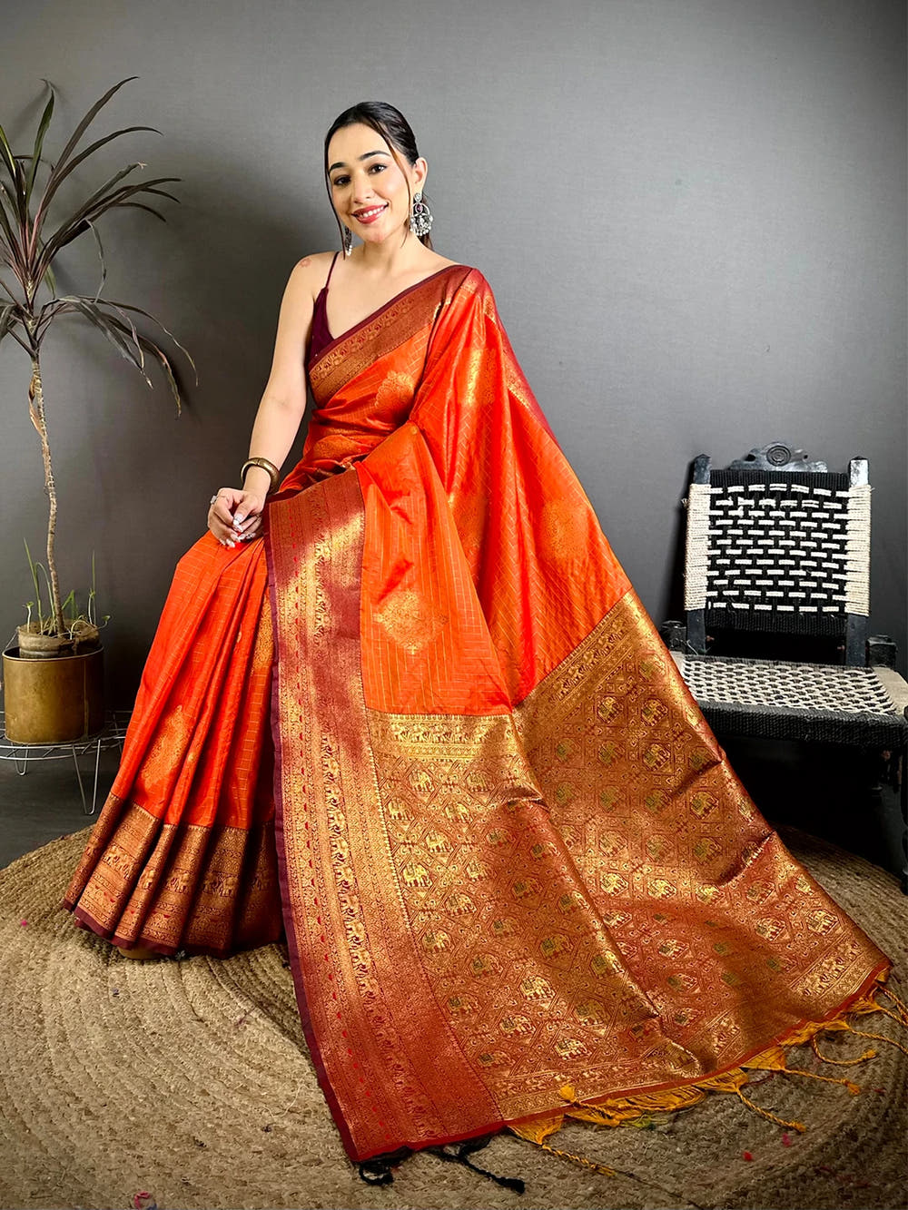 Orange Soft Silk zari check saree, seated pose showing the woven buti motifs on the contrast pallu and border